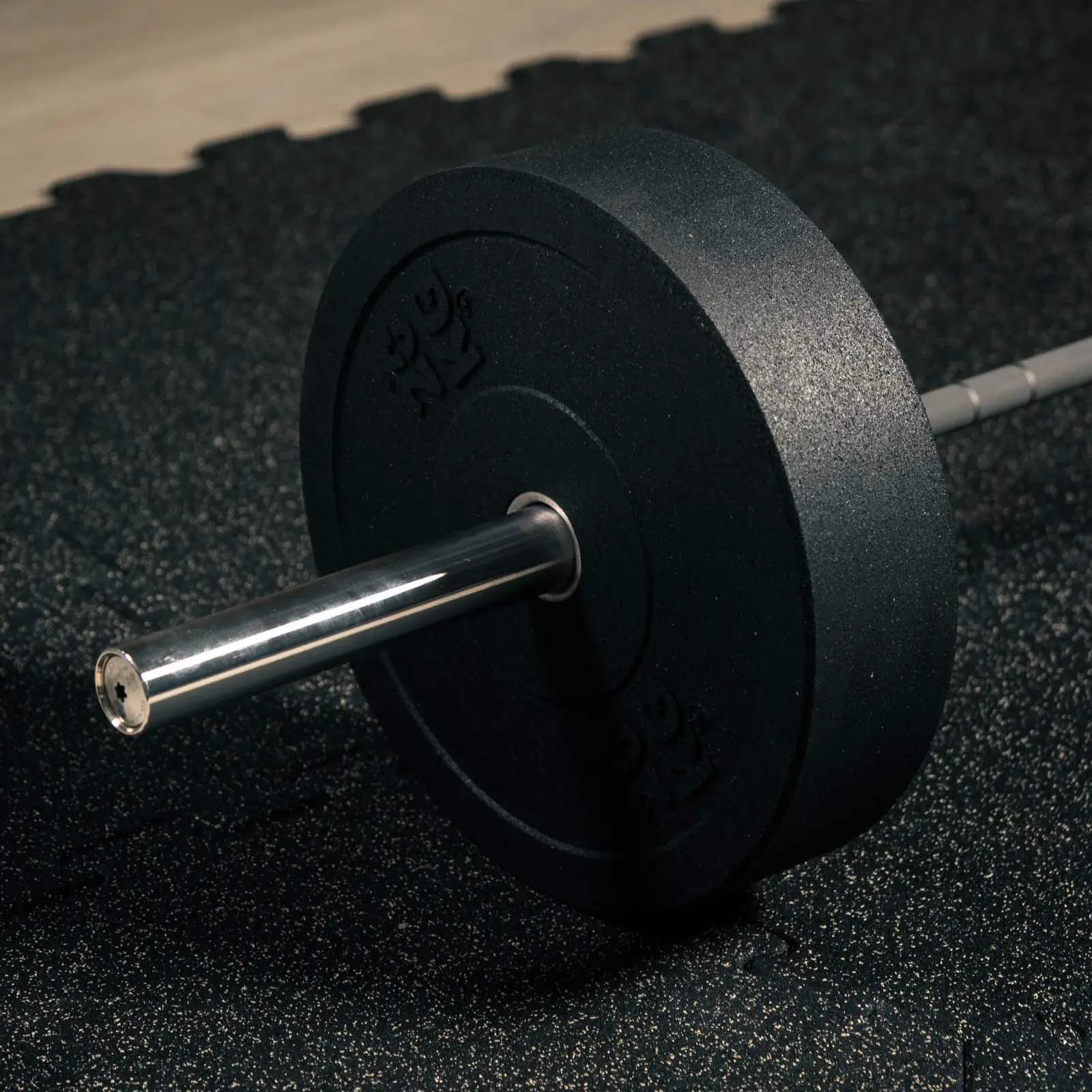Talerz Bumper Essential 20 kg założony na sztangę olimpijską w strefie wolnych ciężarów